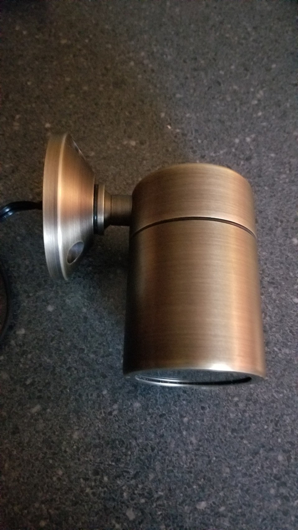 Bronze-colored low voltage light fixture on a dark surface